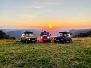trois voitures devant un couché de soleil